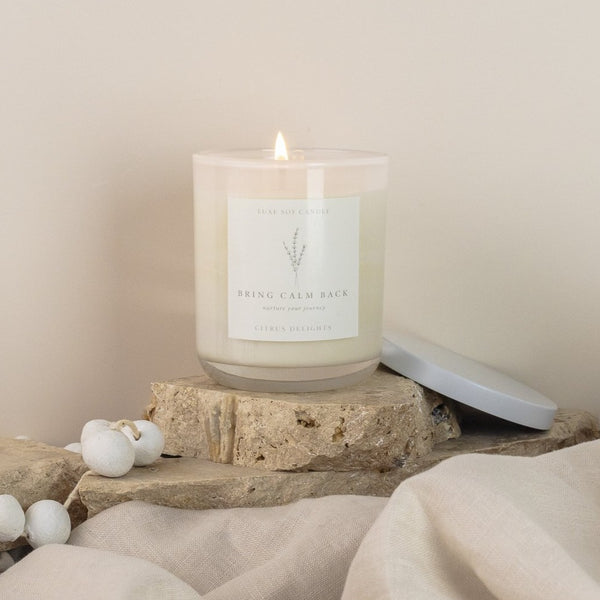 Citrus Delight Candle in a glass jar with a sealable lid and drawstring bag, emitting a fresh and zesty blend of lime, lemon, lemongrass, jasmine, vanilla bean, and rosewood scents. Perfect for moments of relaxation and rejuvenation, transporting you to a citrus orchard or a peaceful sanctuary. Made with 100% natural soy wax, burns for 40+ hours, and packaged to complement any decor.