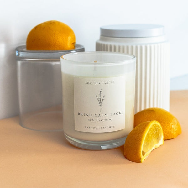 Citrus Delight Candle in a glass jar with a sealable lid and drawstring bag, emitting a fresh and zesty blend of lime, lemon, lemongrass, jasmine, vanilla bean, and rosewood scents. Perfect for moments of relaxation and rejuvenation, transporting you to a citrus orchard or a peaceful sanctuary. Made with 100% natural soy wax, burns for 40+ hours, and packaged to complement any decor.